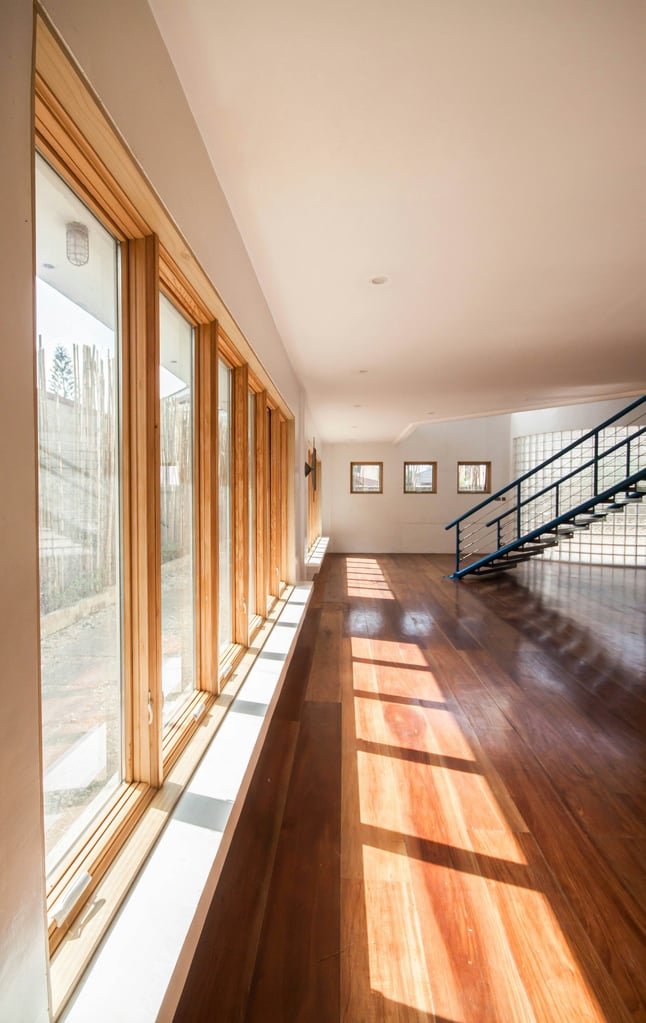Lichtdurchfluteter Raum mit Holzfensterfront und warmem Holzboden
