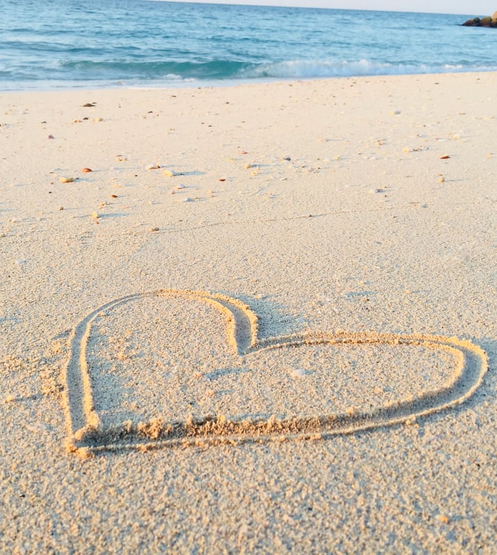 Mit dem Finger gezeichnetes Herz im Sand am Meer