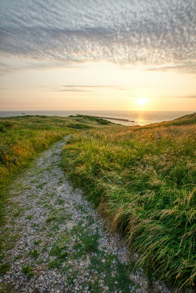 Kiesweg durch Du00fcnengras hinab zum Meer im Sonnenuntergang